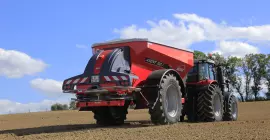 Розкидач добрив AXENT за роботою в полі