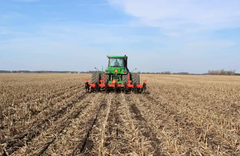 Лінійний розпушувач KUHN Krause 4830 на відстані обробляє ґрунт.