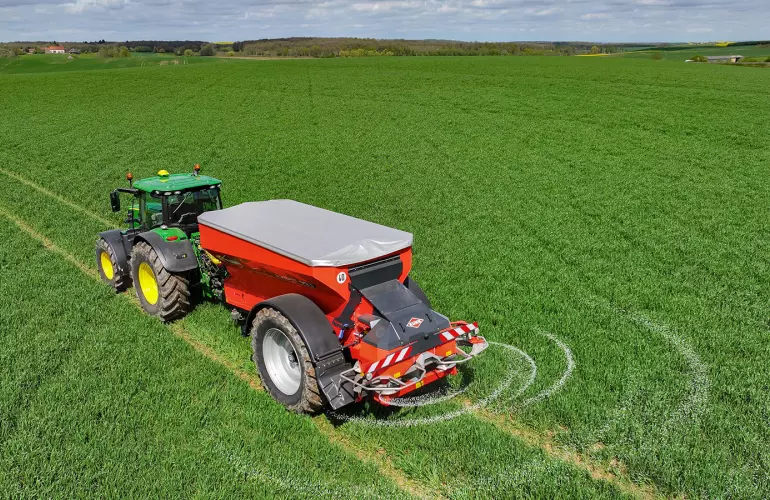 Розкидач добрив AXENT за роботою в полі